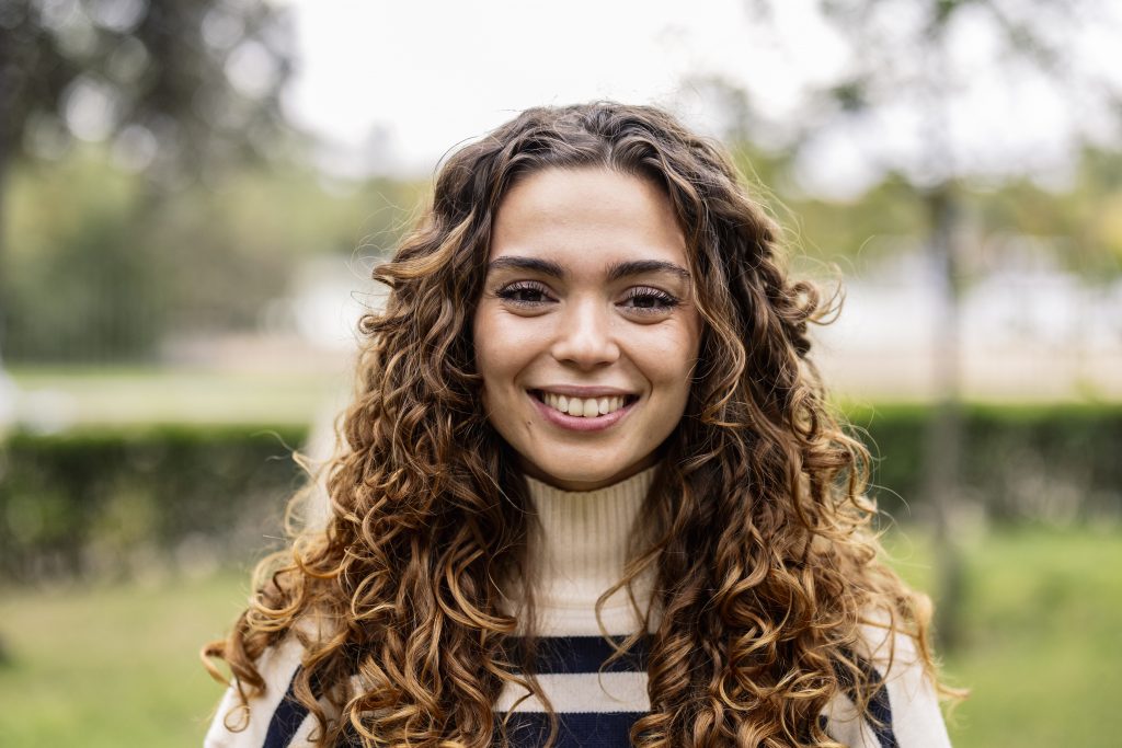 Portrait of young caucasian woman with blonde curly hair smiling and looking at camera